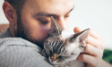 猫を抱き、猫に顔を接触させている男性
